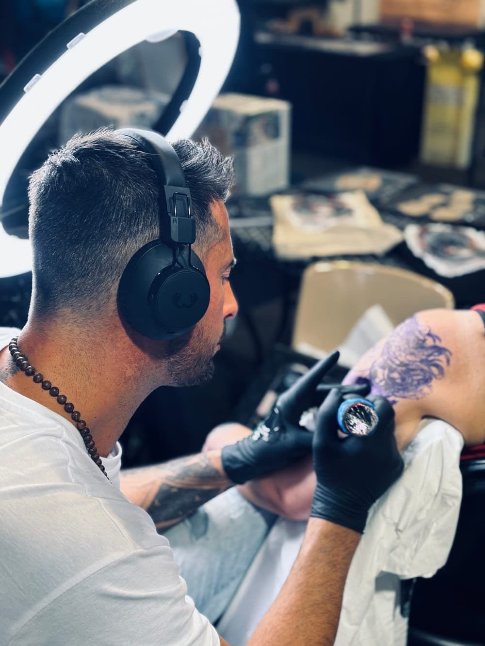 Jarod de profil, concentré, en train de tatouer sous la lumière du studio