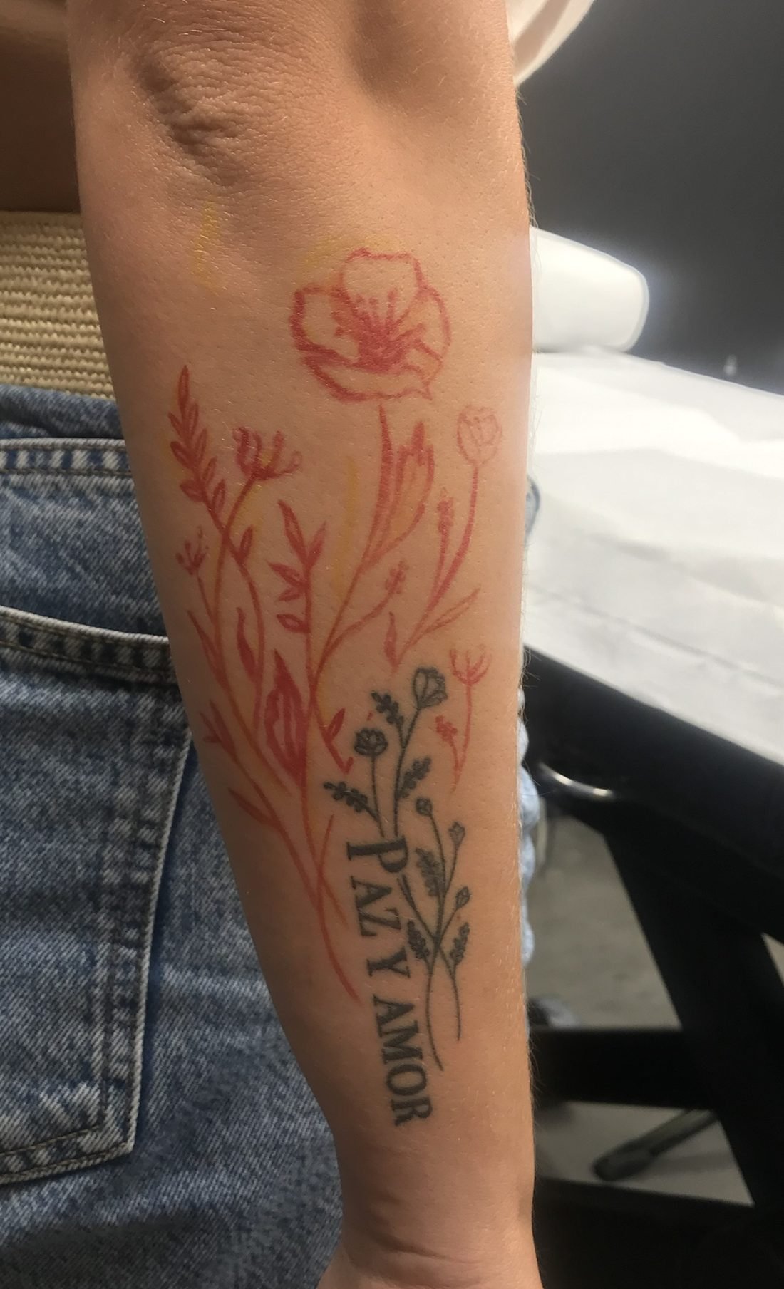 Fleurs dessinées au feutre directement sur la peau autour d’un tatouage existant, avant la séance