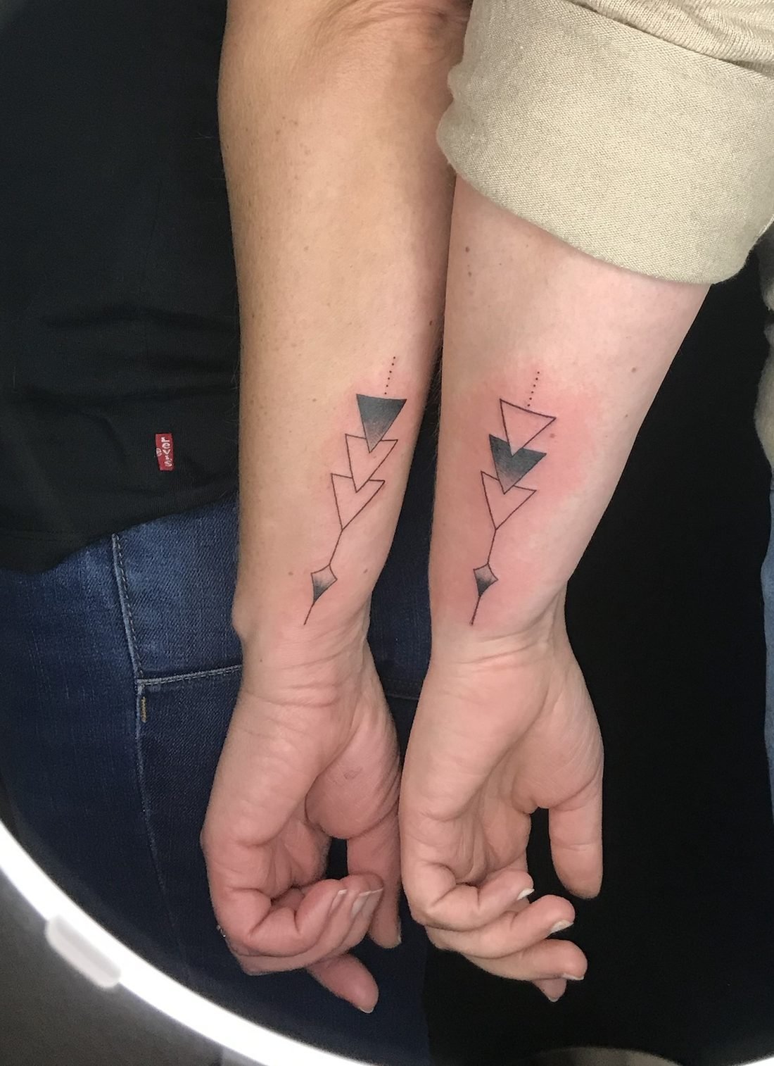 Tatouage en commun à deux : flèches géométriques en trait fin sur deux avant-bras
