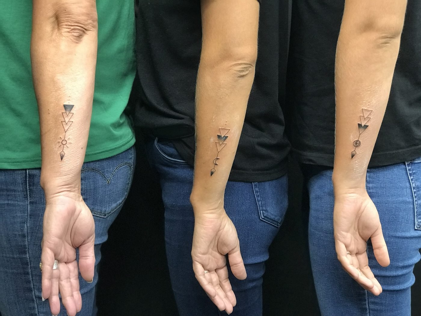 Tatouage en commun à trois : flèches géométriques avec un soleil, une lune et une terre, sur trois avant-bras
