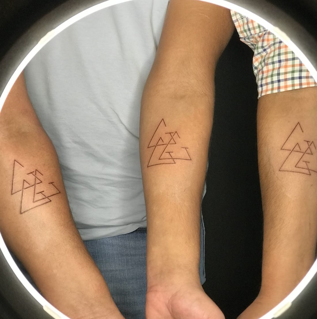 Tatouage en commun à trois : triangles entrelacés en trait fin sur trois avant-bras
