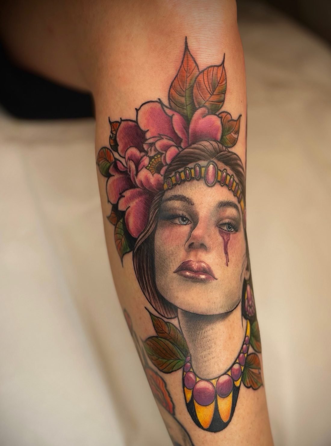 Tatouage néo-traditionnel en couleur : portrait de femme avec une pivoine et des bijoux, sur le tibia